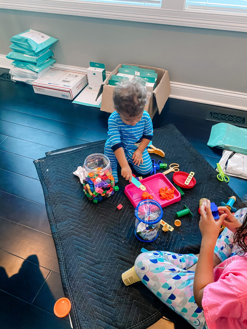 Children sit on a blanket in Nikeytha Ramsey’s home. Junobie products can be seen in the background of the photo. 