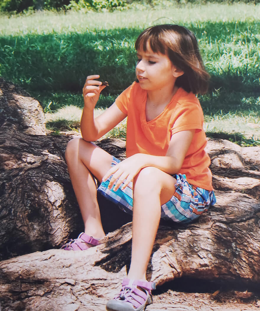 A young Grace sits outside blowing bubbles.