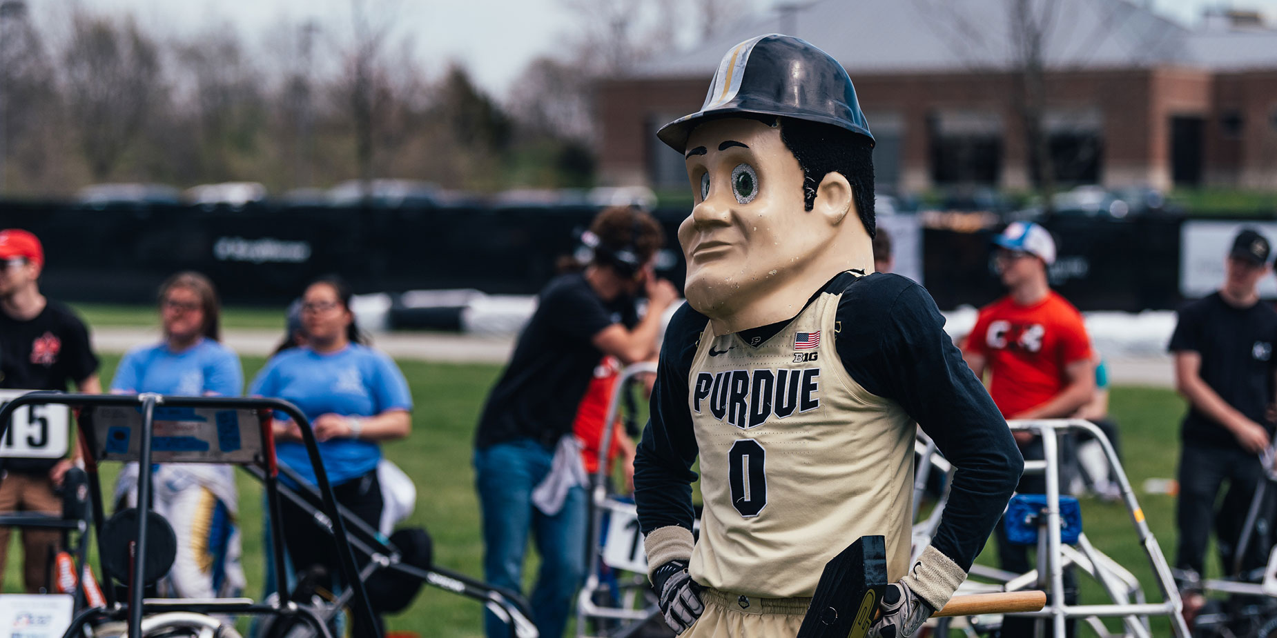 Purdue Pete on the track of the 2022 Purdue Grand Prix, with racing carts and spectators in the background.