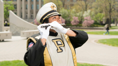 Krupa Patel, a piccolo player in the Purdue “All-American” Marching band, poses with her instrument in her uniform.