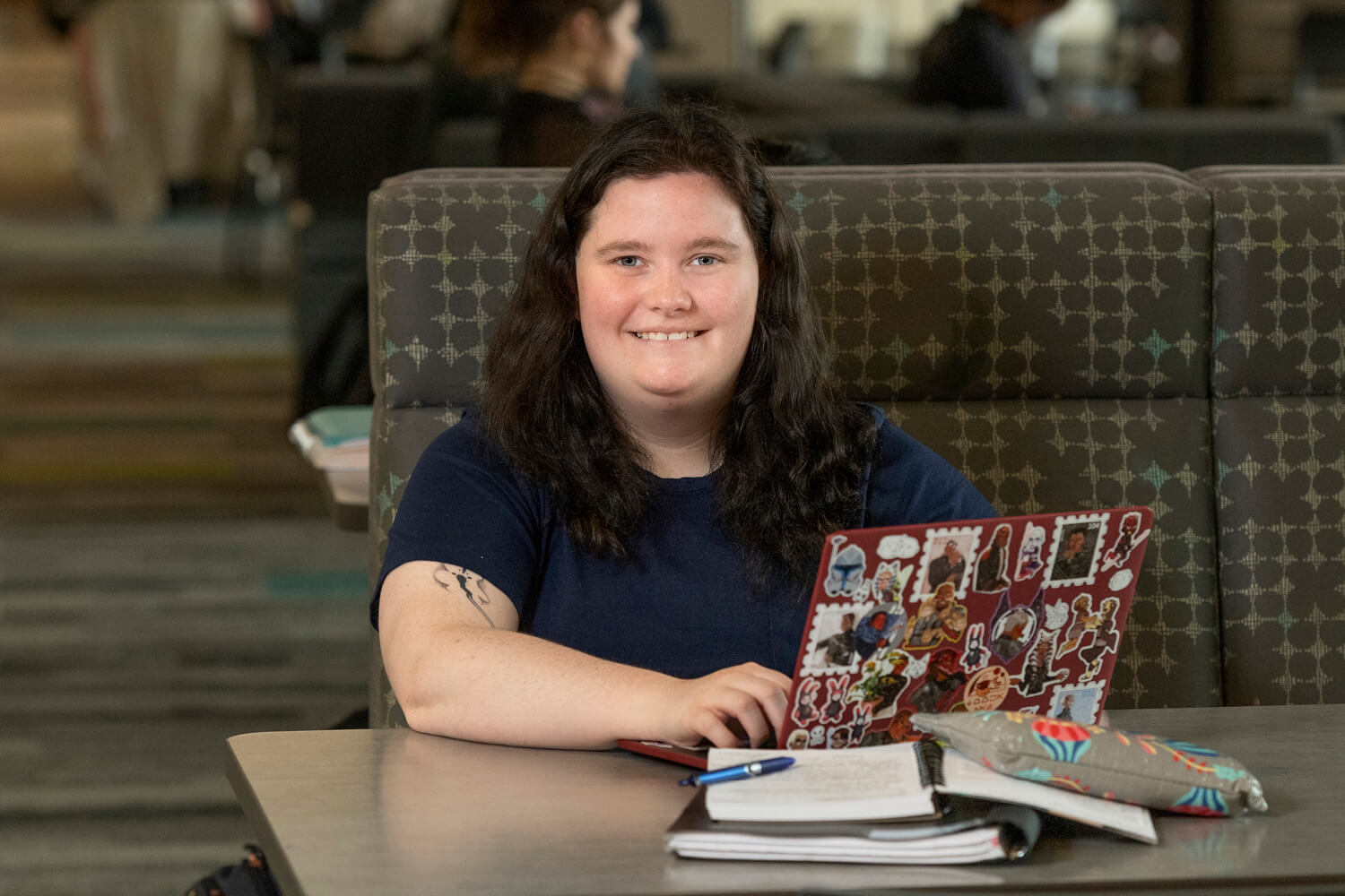 Em studies at a table with their laptop.