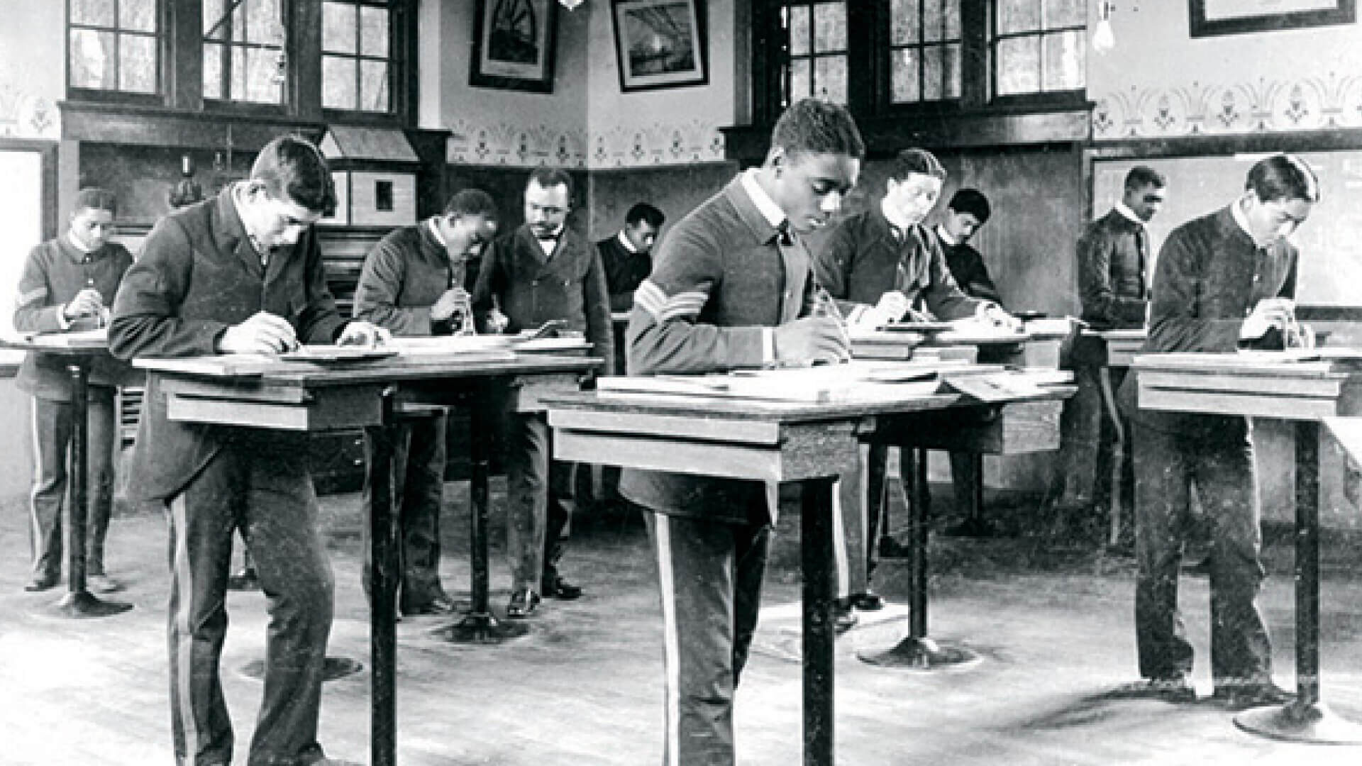 Photo of Lewis teaching in a classroom of students at desks.