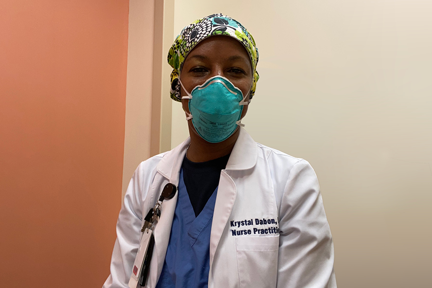 Krystal Dabon wears a surgical mask, scrubs and lab coat.