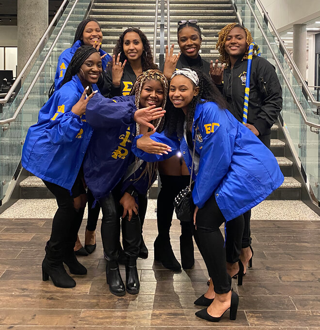 Deverieux Coleman and six Sigma Gamma Rho sisters show their hand signs