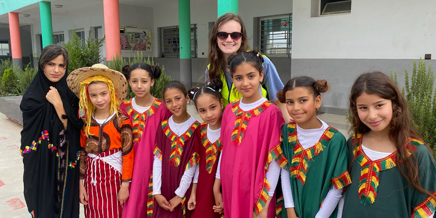 Alexia smiles behind a group of eight Moroccan children in traditional dress