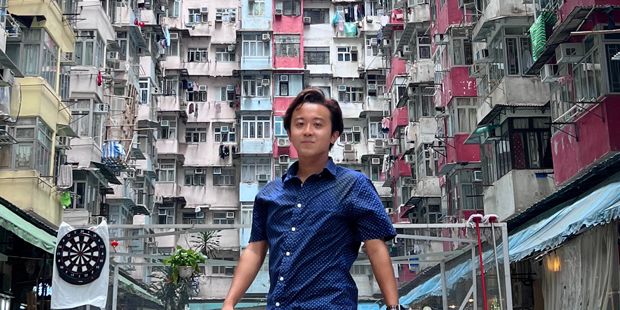 Nick poses in front of colorful high-rise apartments