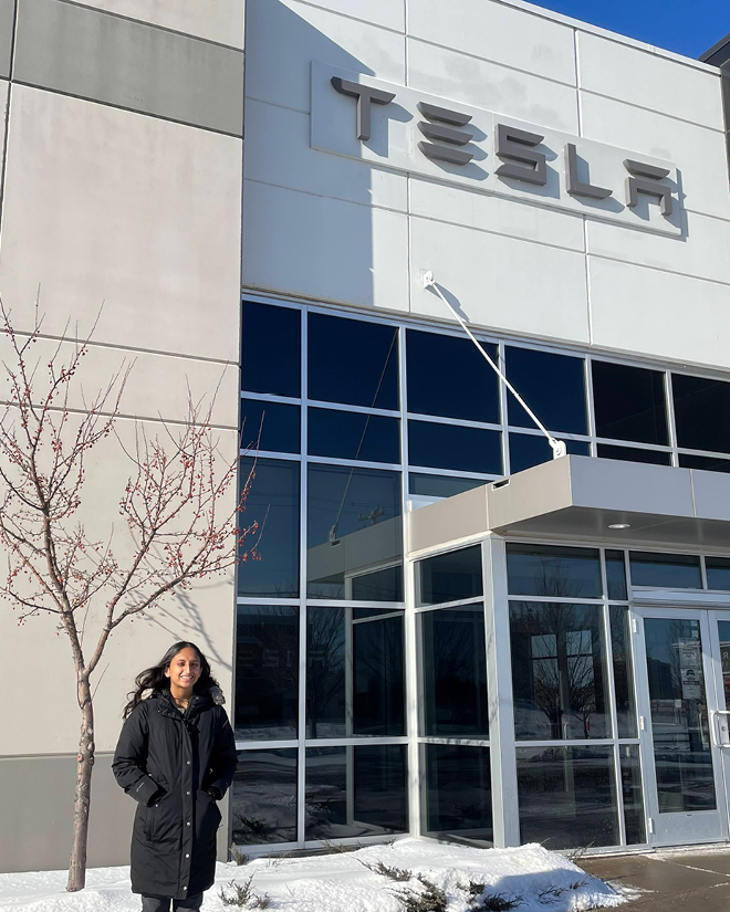 Pooja stands outside the Tesla building