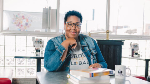 LaQuinta seated at a table in a coffee shop, with books and a coffee cup in front of her.