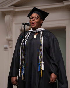 LaQuinta dressed in graduation robes, performing the national anthem.