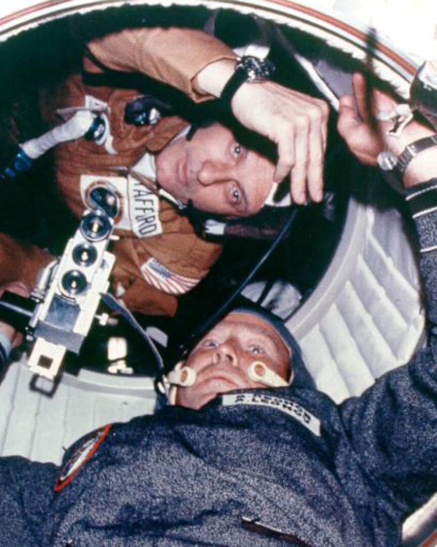 Astronaut Thomas Stafford and cosmonaut Aleksei Leonov meet in the hatchway connecting the Apollo spacecraft and Soyuz capsule.