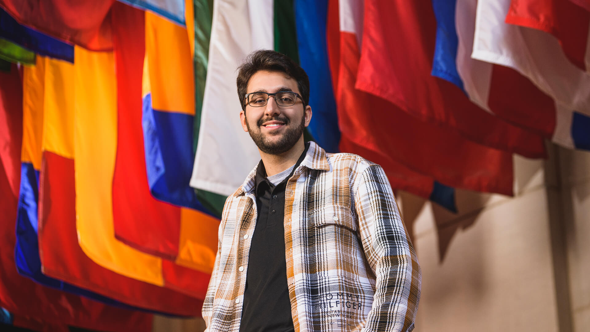 Parsia Bahrami stands in front of a collection of flags.