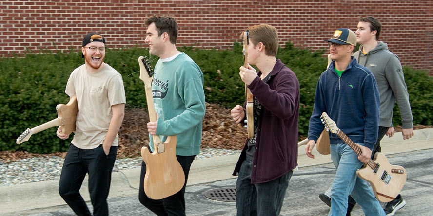 Students holding the guitars they have built in MET 34900.