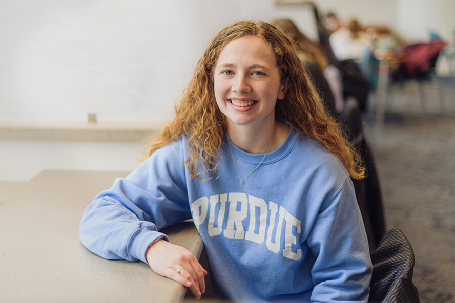 Matlyn Miller smiles at the camera while sitting in a classroom.