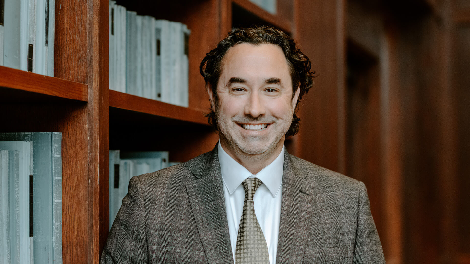 Michael Witt in front of bookshelf.