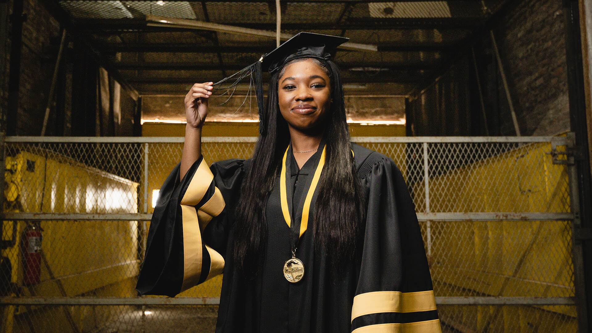 Sanai Johnson pulling graduation cap tassel.