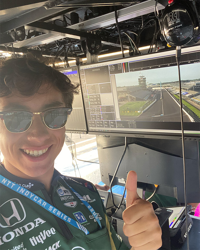 Zach MacNab gives a thumbs-up while standing in front of a simulation screen.