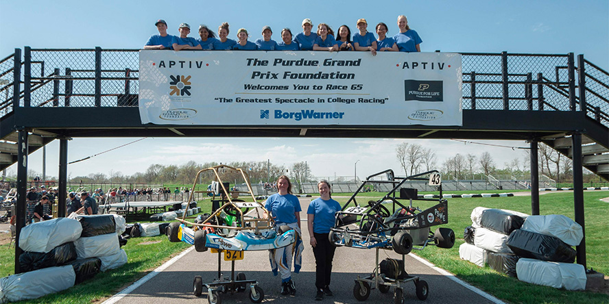 Members of the Society of Women Engineers gathered around the raceway arch at the 2022 Purdue Grand Prix.