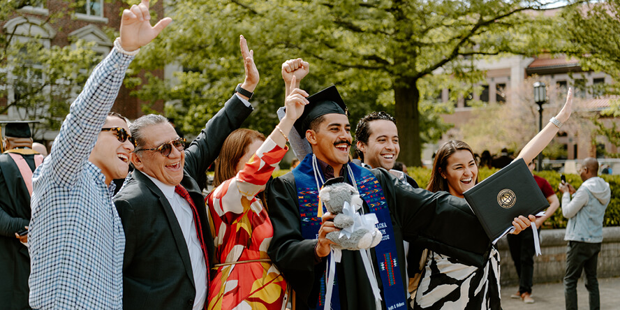 Wearing a cap and gown, Montes and his family cheer in celebration.