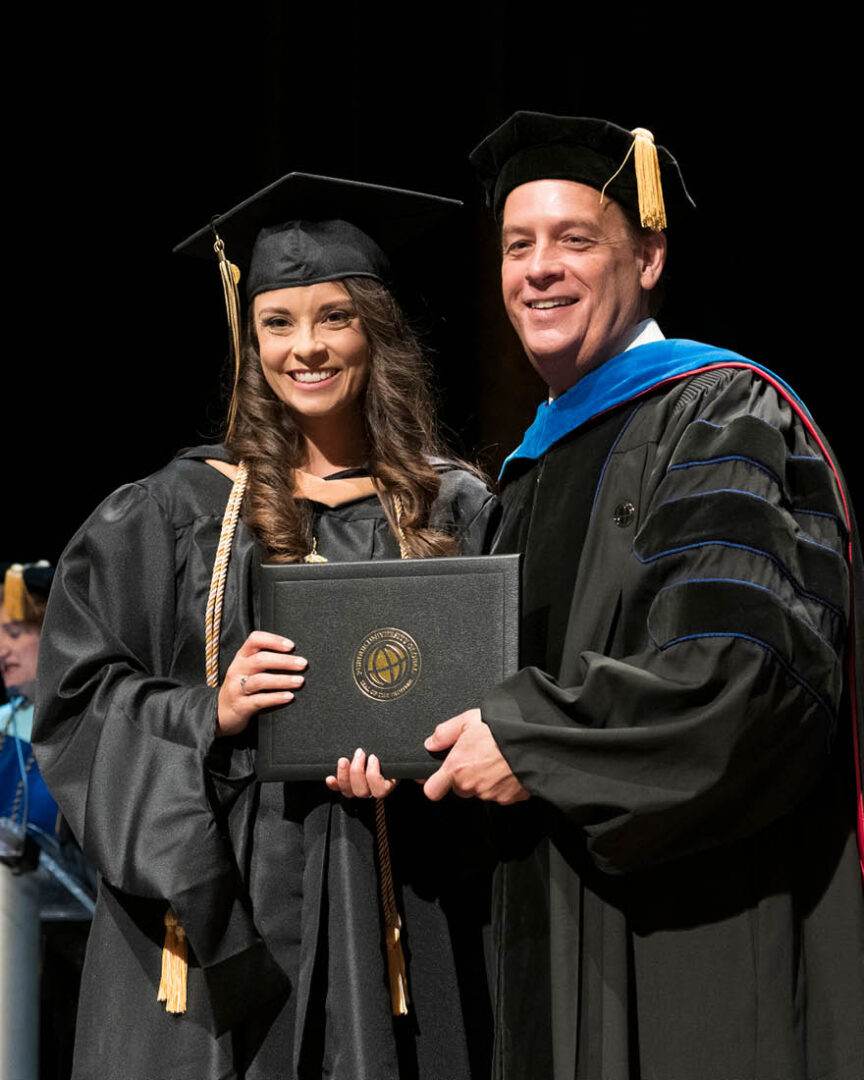 Bruso poses for a photo with the dean as she receives her MBA at Purdue Global’s May 2023 commencement