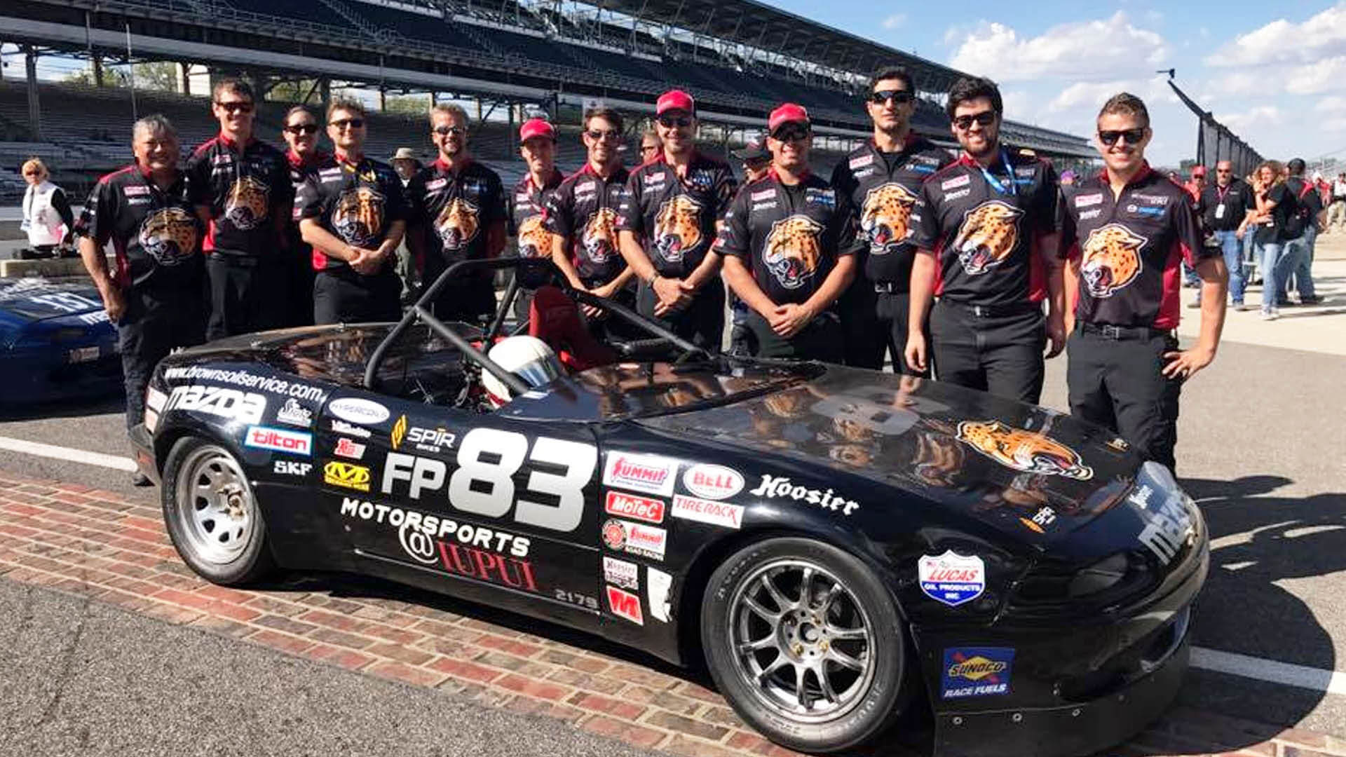 Students involved in the motorsports engineering program standing on the track.