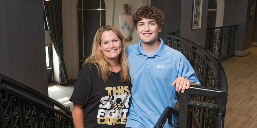 Andrew Kinder and his mother, Betsy, in the main living area inside the Beta Theta Pi house.