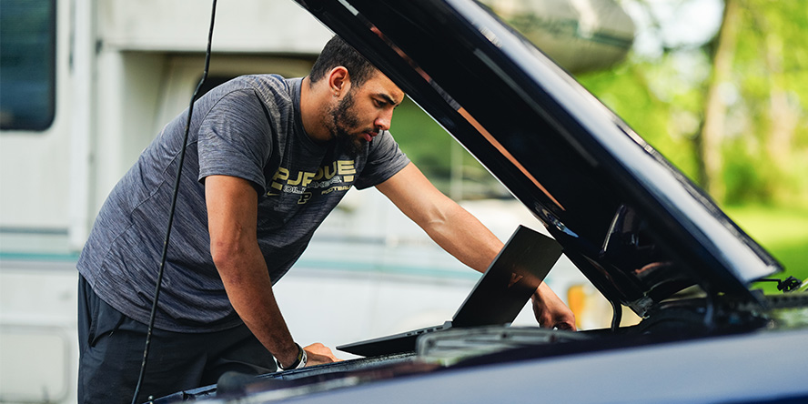 Devin Mockobee looks under the hood of a car