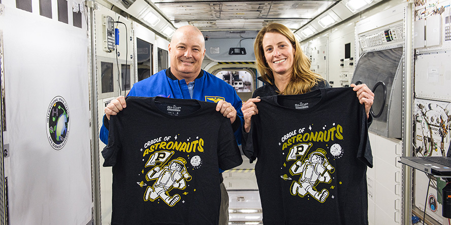 Purdue astronauts Scott Tingle and Loral O’Hara hold up Purdue “Cradle of Astronauts” T-shirts