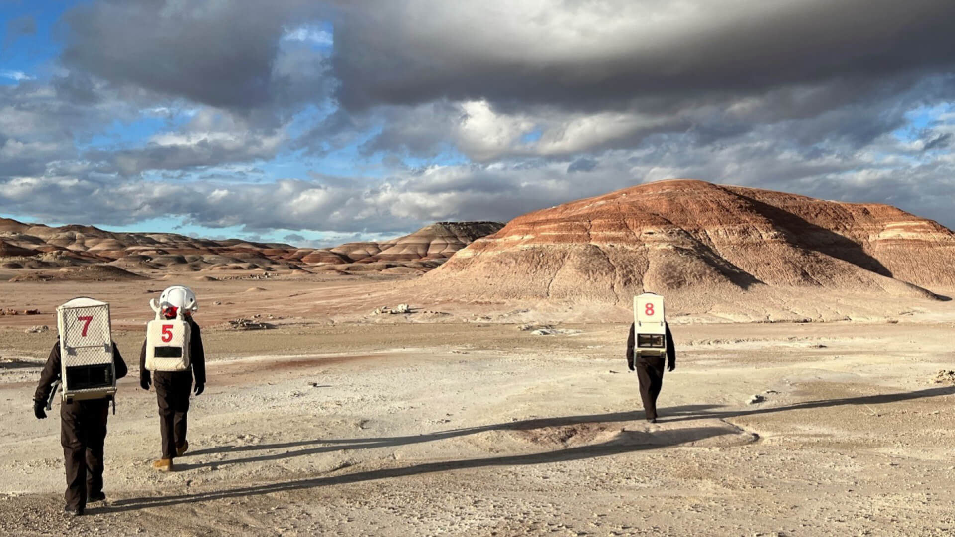 Three Purdue students walk through the barren Utah desert landscape, bearing similarities to Mars.