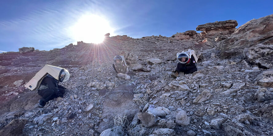 Three Purdue students wearing breathing devices explore the Utah landscape, noted for its similarities to Mars.