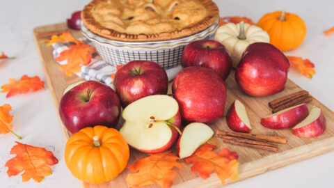 Apple varieties next to an apple pie.