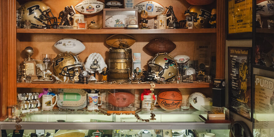 A bookshelf stocked with Purdue-related items that displays only a small fraction of Chris Pate’s Boilermaker collection 