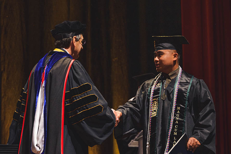 Clifford Manuel shaking hands at graduation ceremony.