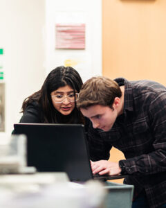 Ishita Sameer Bhedi and a peer looking at a laptop.