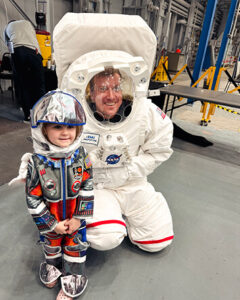 Waggle in an xEMU prototype suit interacting with the public at the 2023 Eclipse Open House at Johnson Space Center during his first NASA Pathways tour, October 2023. (Photo courtesy of Jessica Krenzel)