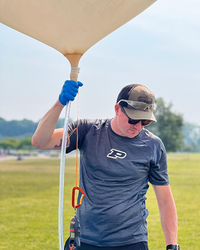 Waggle pre-launch of SEDS weather balloon, finalizing helium fill and checking for correct buoyancy, June 2023. (Photo courtesy of Abra Bailey)
