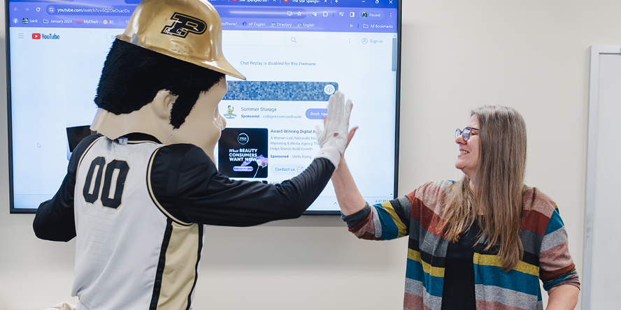 Purdue Pete high-fives Linda Haynes at the front of her classroom.