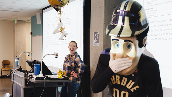 Associate professor Kendra Erk stands at the front of her classroom with Purdue Pete.