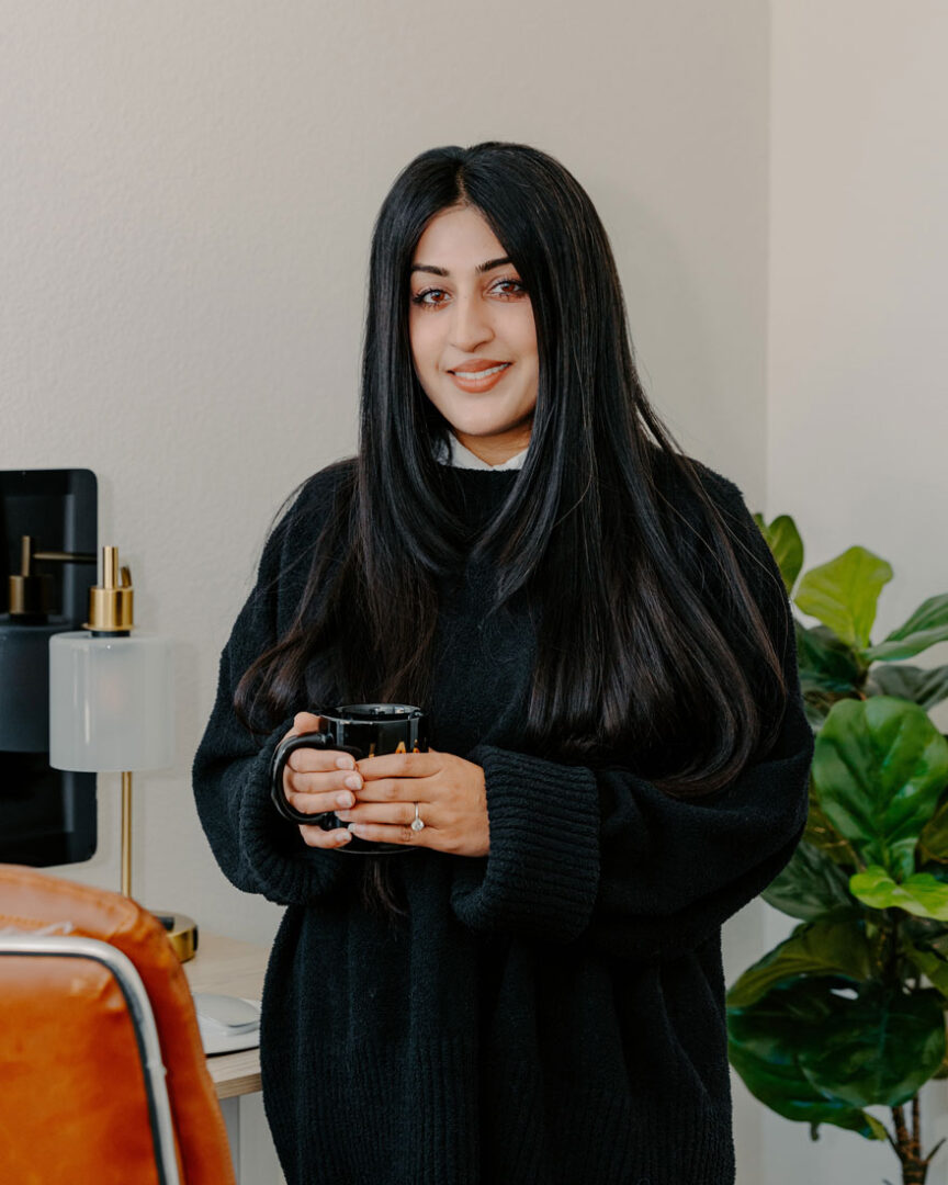 Rana stands next to her desk, a black mug in her hands. 