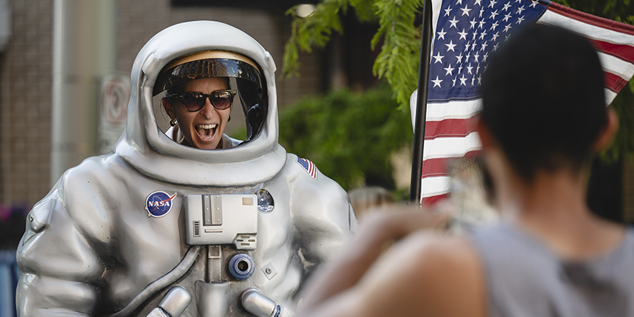 A woman takes a photo in a prop astronaut suit at USA Swimming LIVE presented by Purdue.