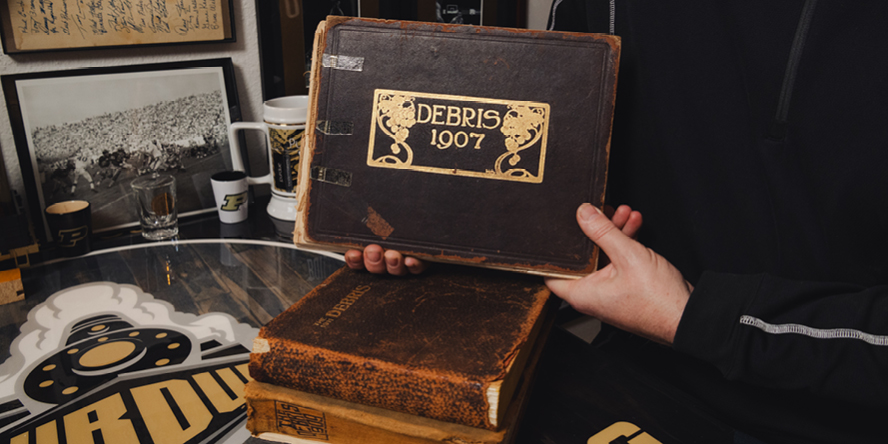 Casey Stultz holds a copy of the 1907 Purdue Debris yearbook.