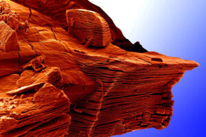 Art depicting a red cliff against a blue background.