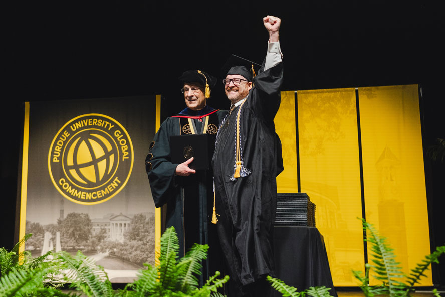 Craig Dockstader and Purdue Global Chancellor Frank Dooley onstage at graduation.