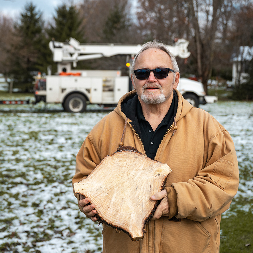 Darrell Smith holds up a section cut from the tree he donated.