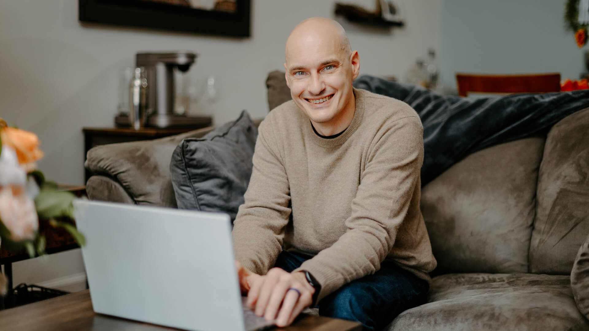 Kevin sits at home on the couch, with his laptop open on the coffee table.