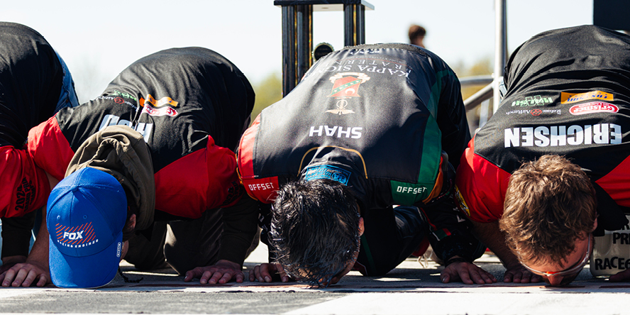 The Kappa Sigma Racing A team kisses the bricks at the start/finish line of the Purdue Grand Prix track