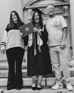 Tara poses with her mom on one side and her dad on the other, holding her diploma on the steps of Hovde Hall in West Lafayette, Indiana.