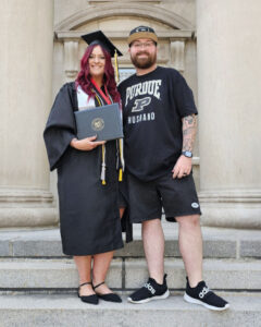 Tara poses next to her husband on campus, whose shirt reads “Purdue husband.”