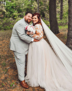 A wedding photo of Tara and her husband taken in the woods.