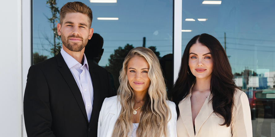 A picture of the three founders of Vitality in front of a glass window.