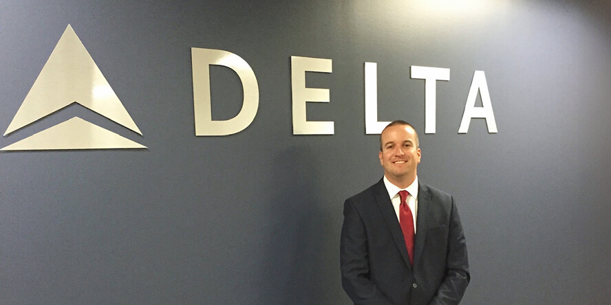 Greg Etter in front of a Delta sign.